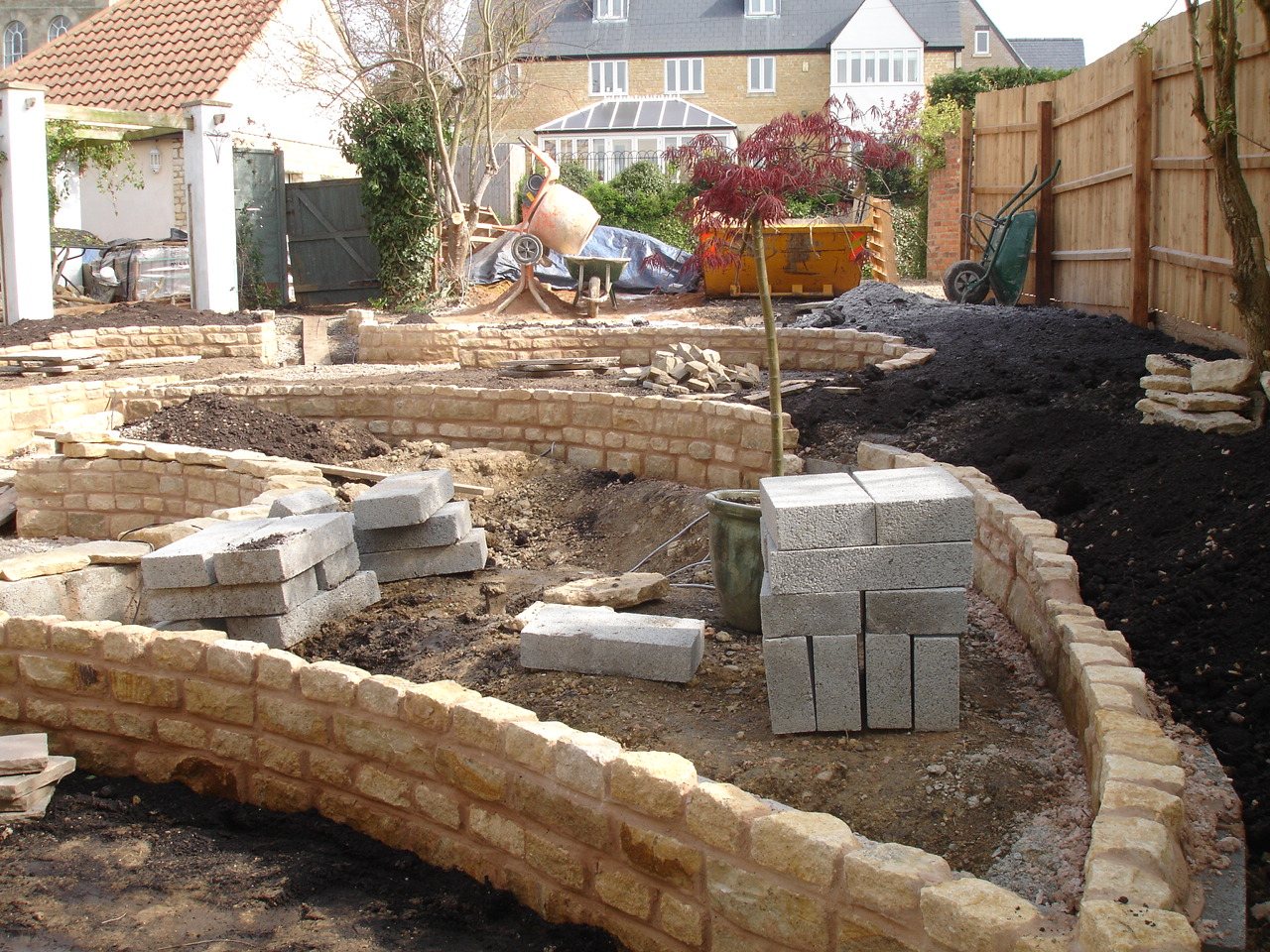 Before: Curved stone raised beds going in, then planted up.