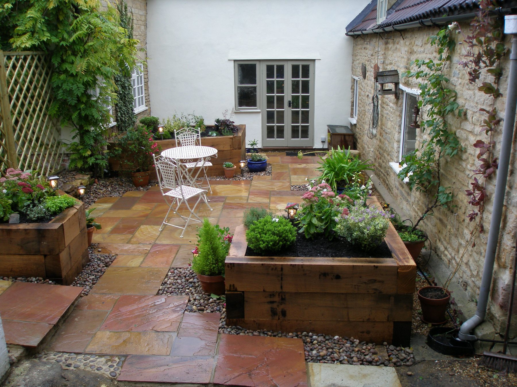After: A dug-out courtyard, paved in sandstone with sleeper raised beds.