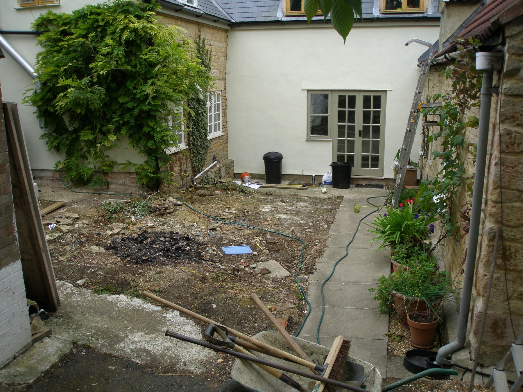 Before: A dug-out courtyard, paved in sandstone with sleeper raised beds.