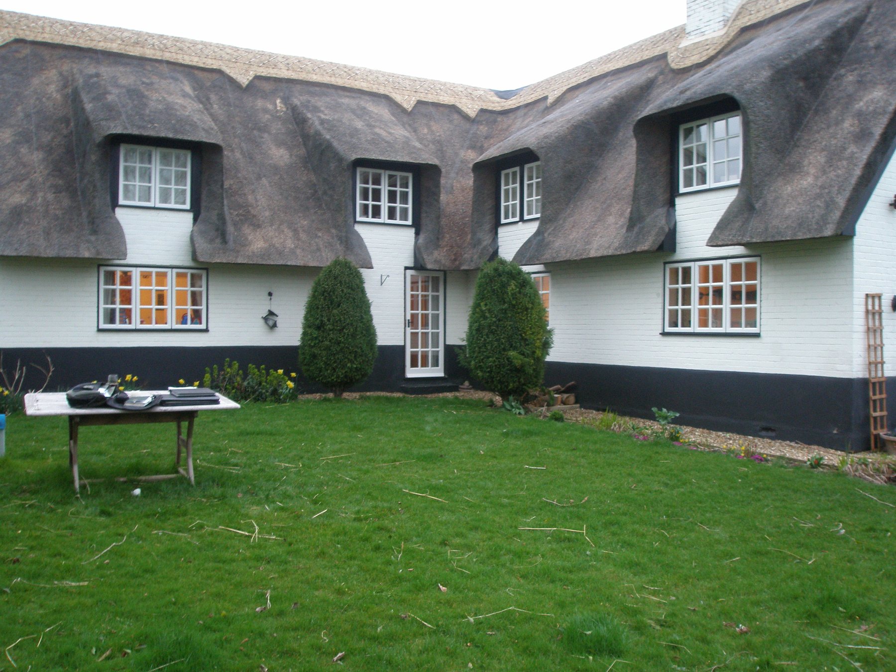 Before: A plain lawn behind a thatched cottage, turned into a terrace with rendered raised beds.