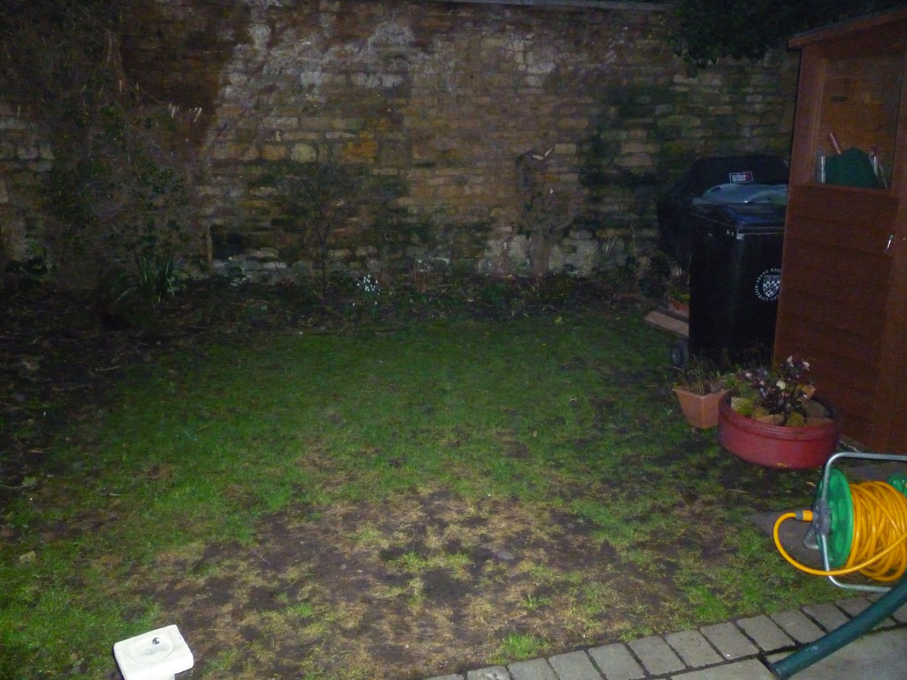 Before: A dark corner by a stone wall, now a circle-pattern patio with an arbour seat.