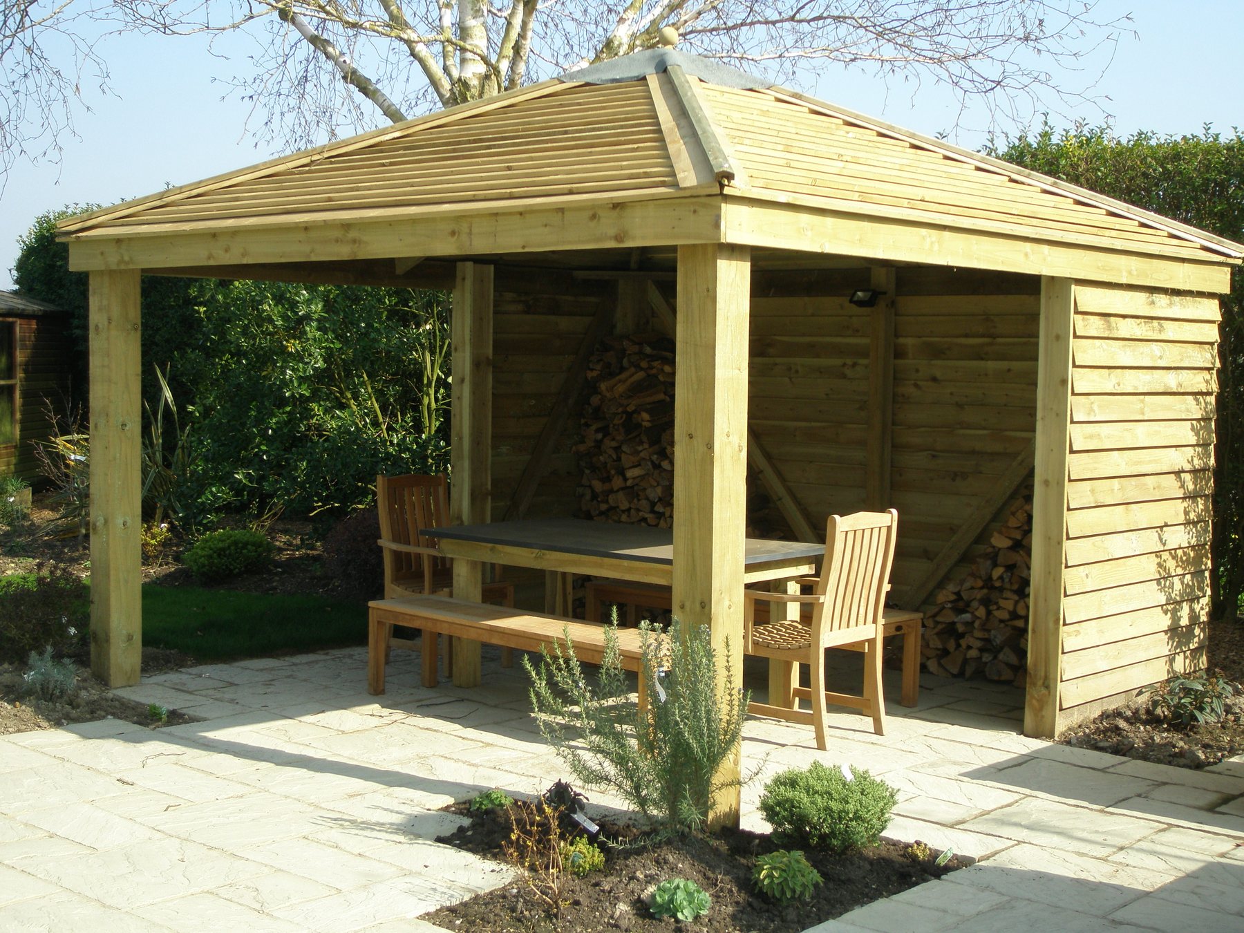 Open timber shelter with a log store and dining table
