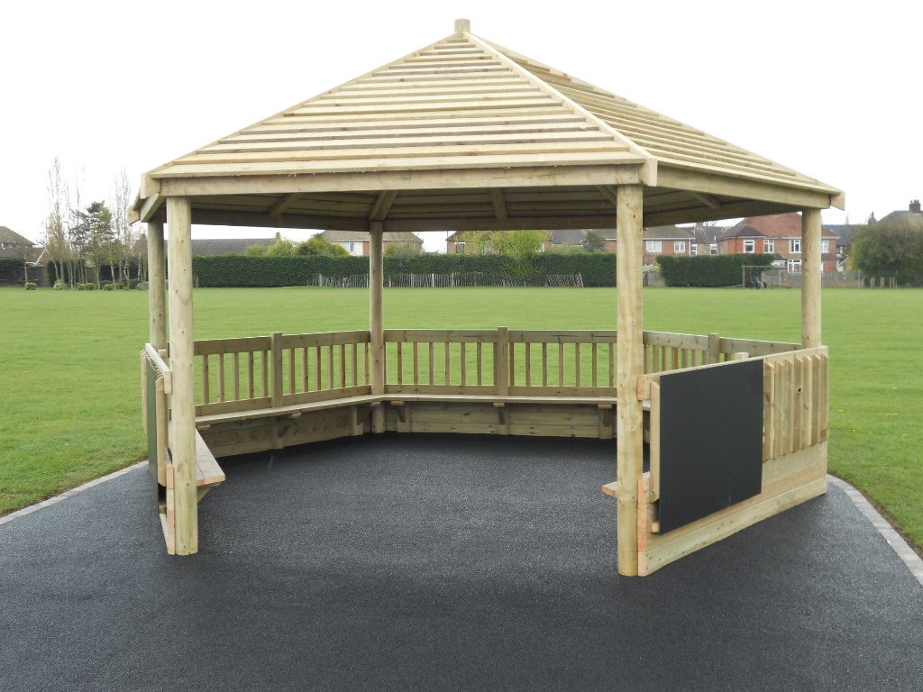 Octagonal timber outdoor classroom with a chalkboard on a school field