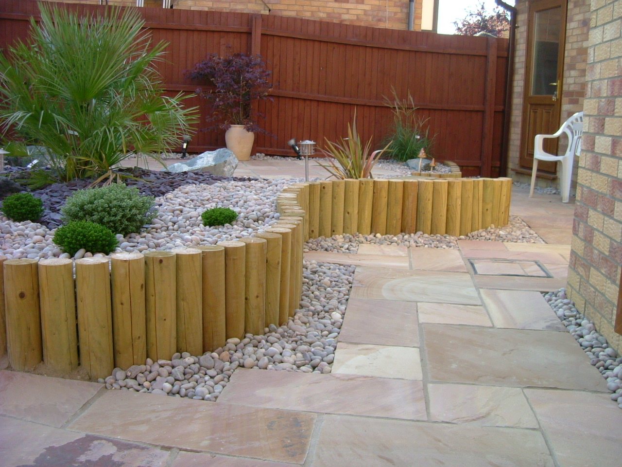 Sandstone paving edged with curved log rolls and slate chippings
