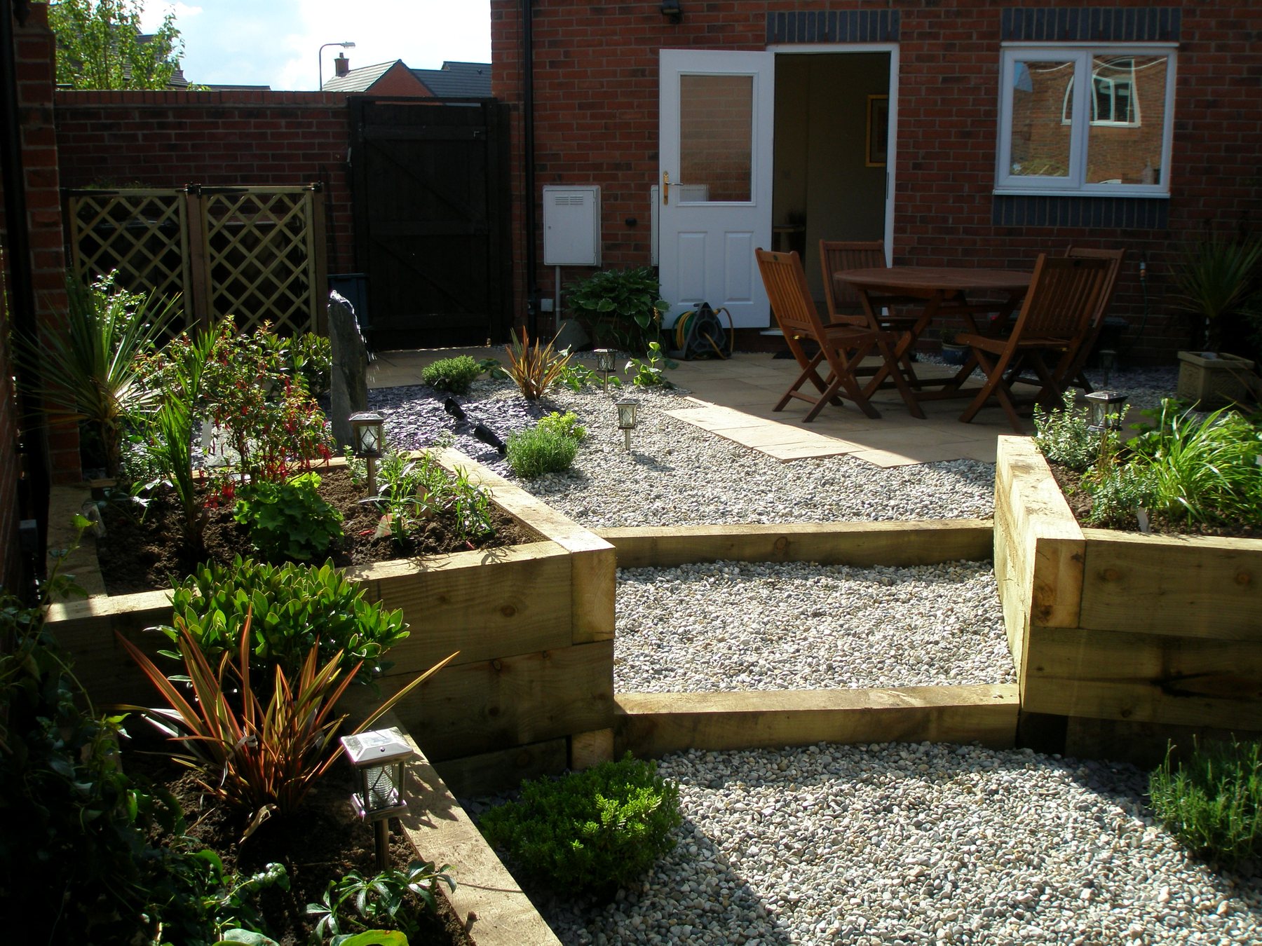 Sleeper raised beds and a gravel terrace with a dining set