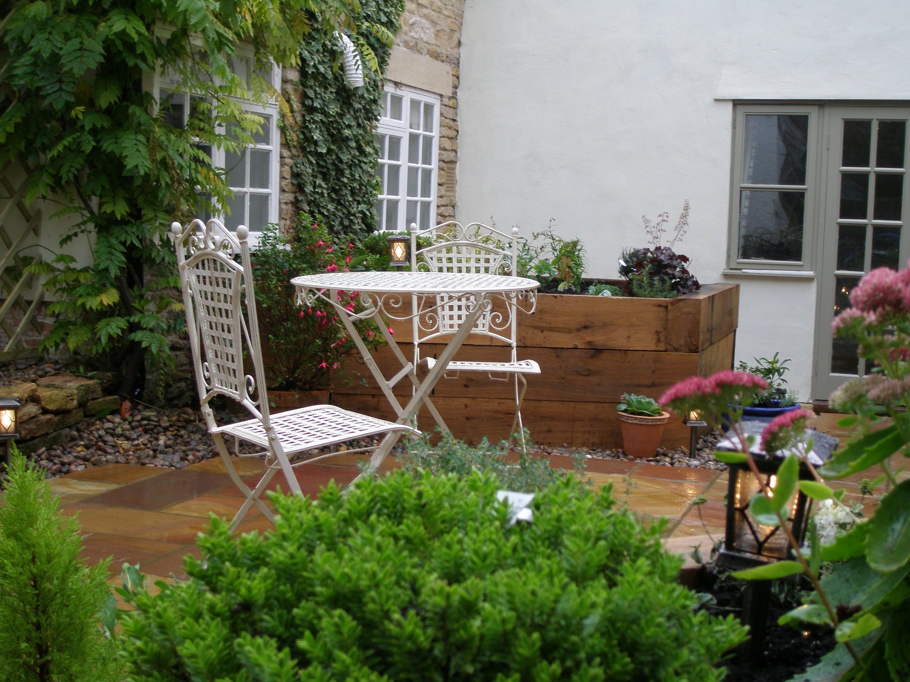 Cottage patio with a white iron bistro set and sleeper beds