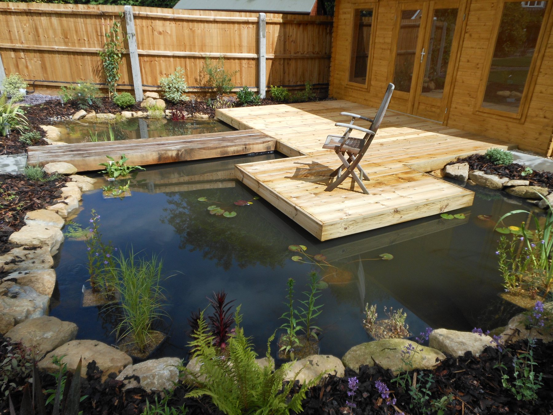 Pond with a floating timber deck and stone edging