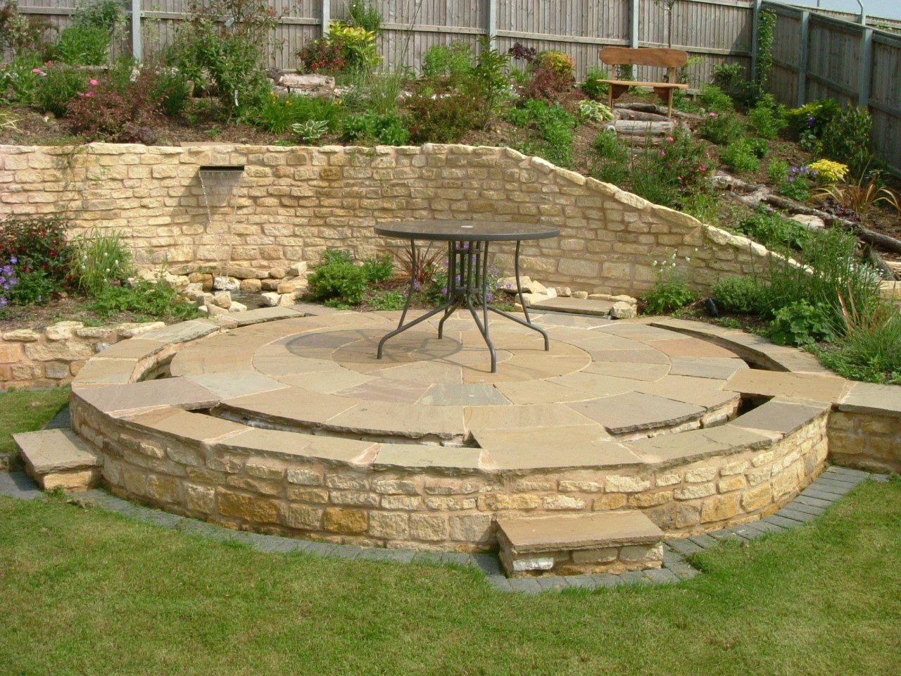 Raised circular stone patio set into a stone retaining wall