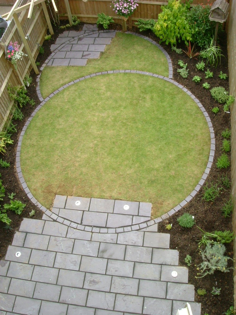 Two circular lawns joined by paved steps with lights
