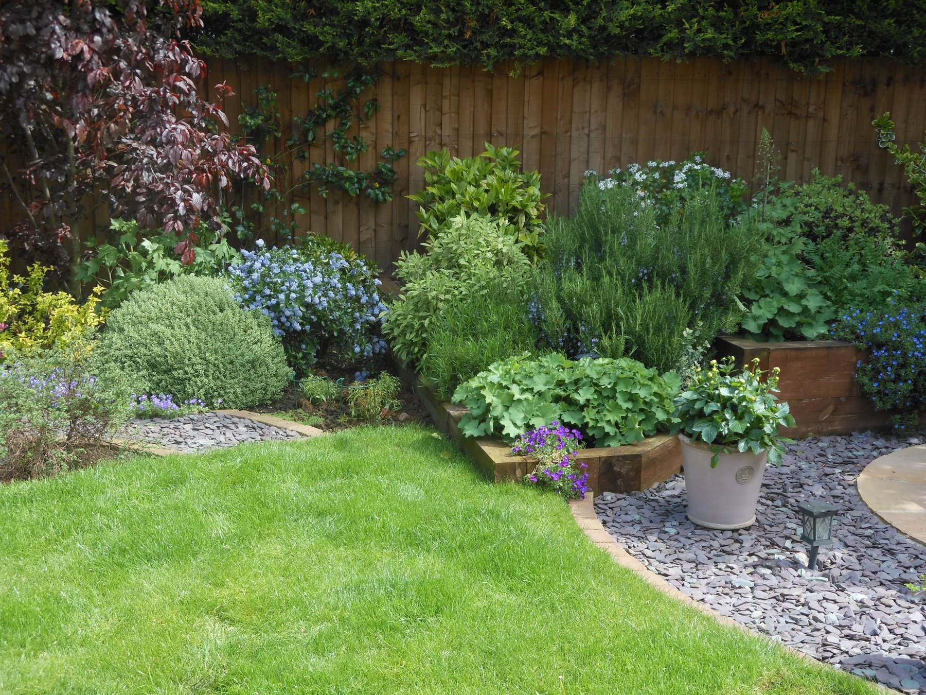 Border with a sleeper bed and slate mulch beside a lawn