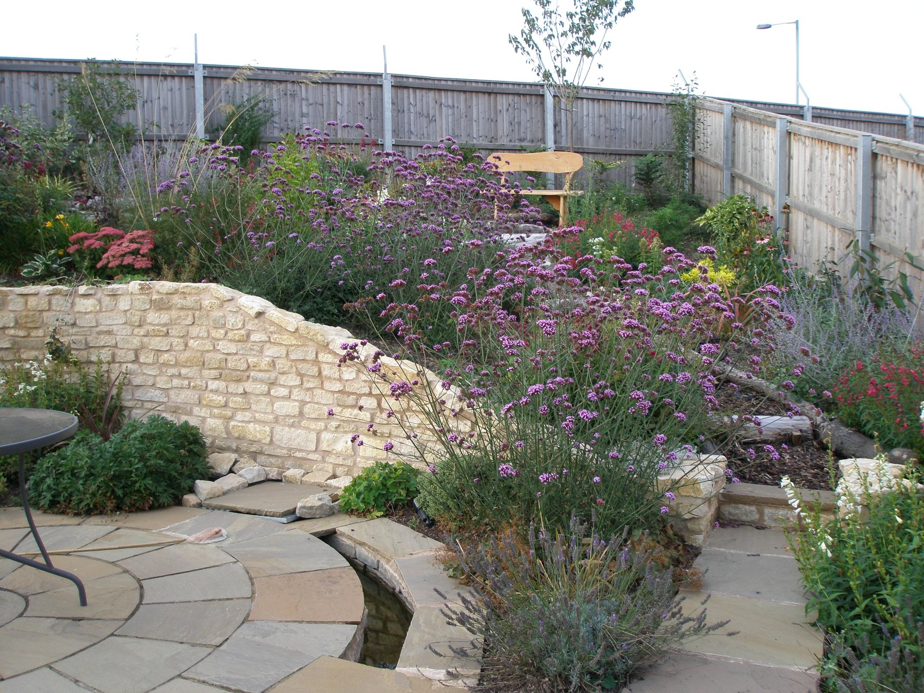 Curved stone walls with prairie-style planting and a rill
