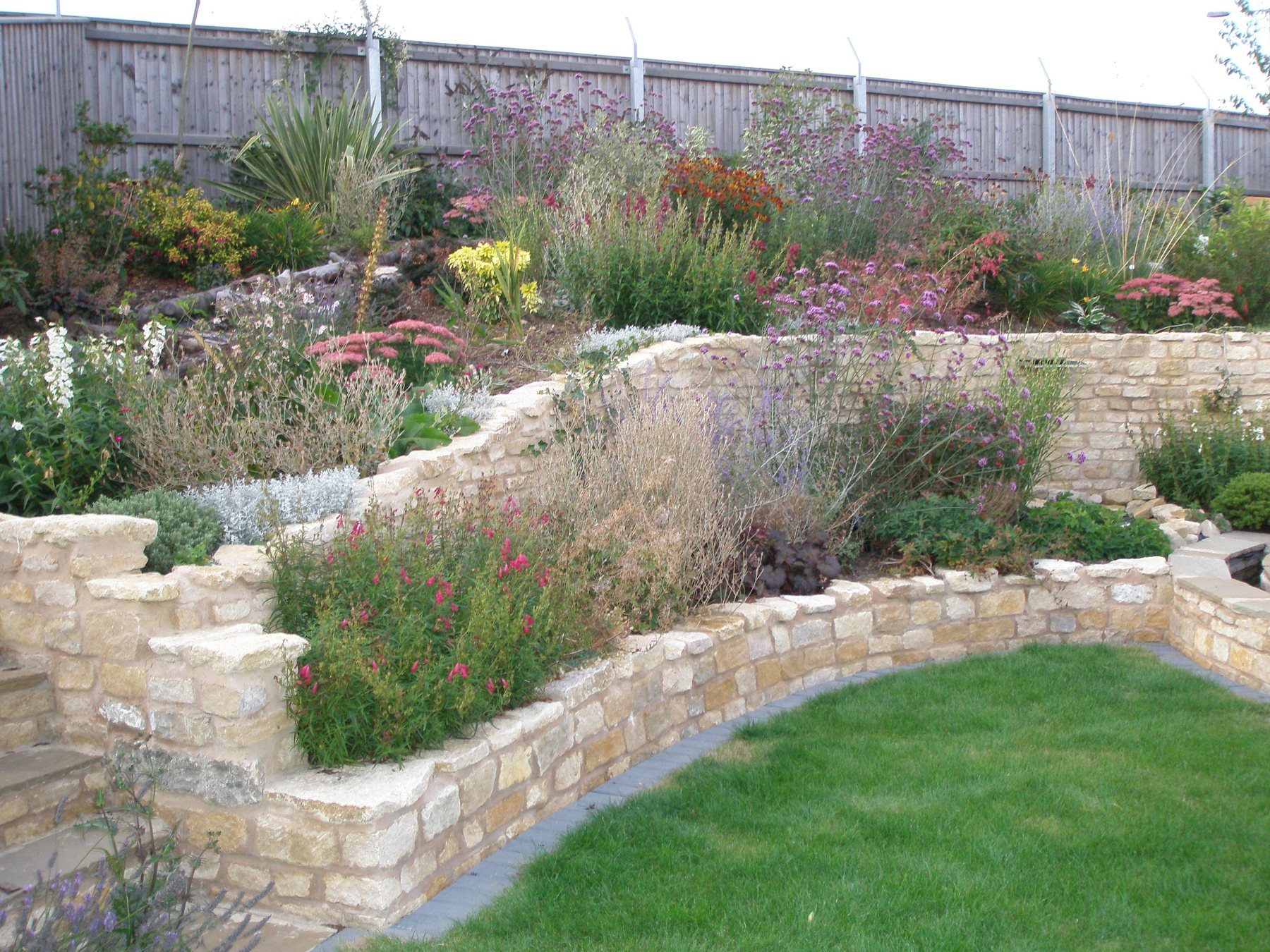 Terraced stone walls with planting above a lawn