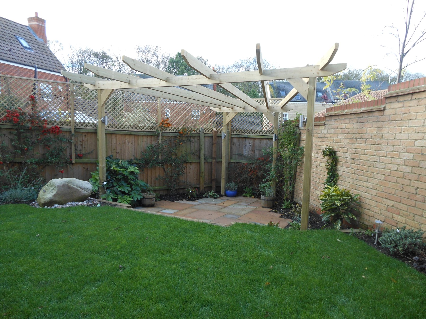 Timber pergola running along a brick wall above a lawn