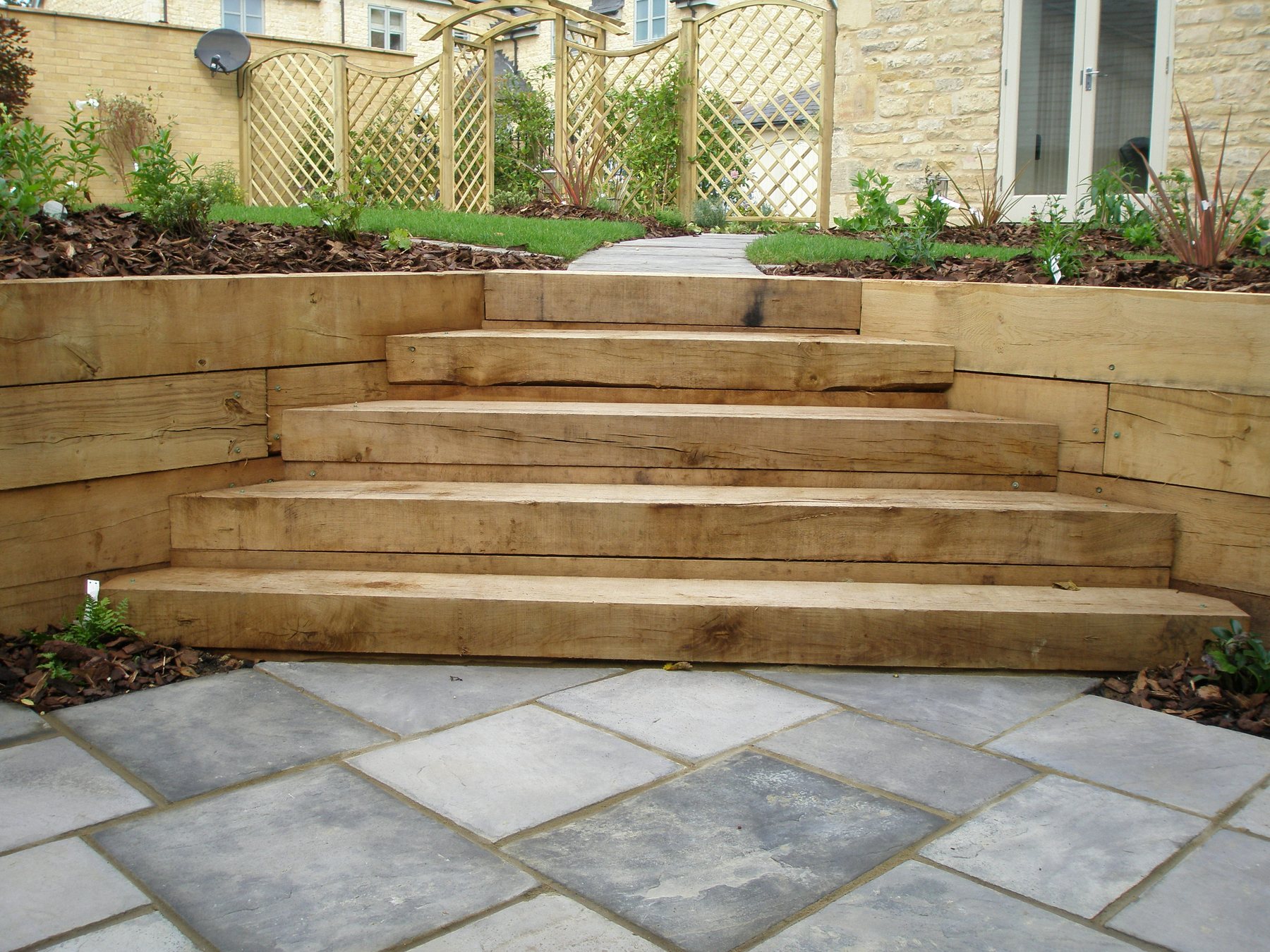 Oak sleeper steps leading down to a stone terrace